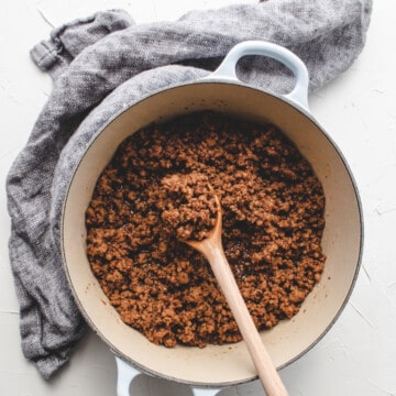 Taiwanese mined pork sauce in a blue Dutch oven with grey linen cloth on the side.