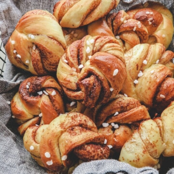 two cardamom cinnamon buns with pearl sugar in top in the basket.