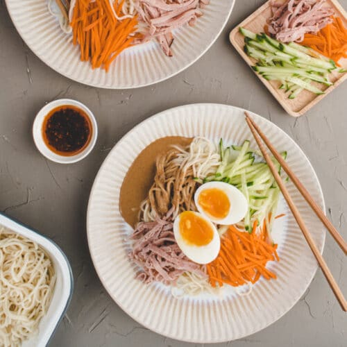 two plates of Taiwanese cold sesame noodle with chili oil on the side.