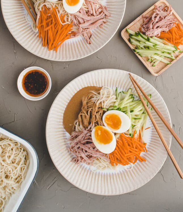 two plates of Taiwanese cold sesame noodle with chili oil on the side.