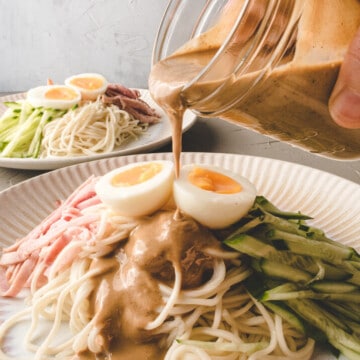 pouring dressing over sesame cold noodle.