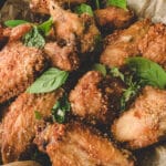 air fry chicken wings and basil on parchment paper in a black skillet.