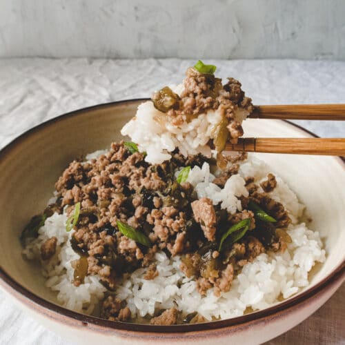 chopstick, a bowl of rice top with ground pork and scallion