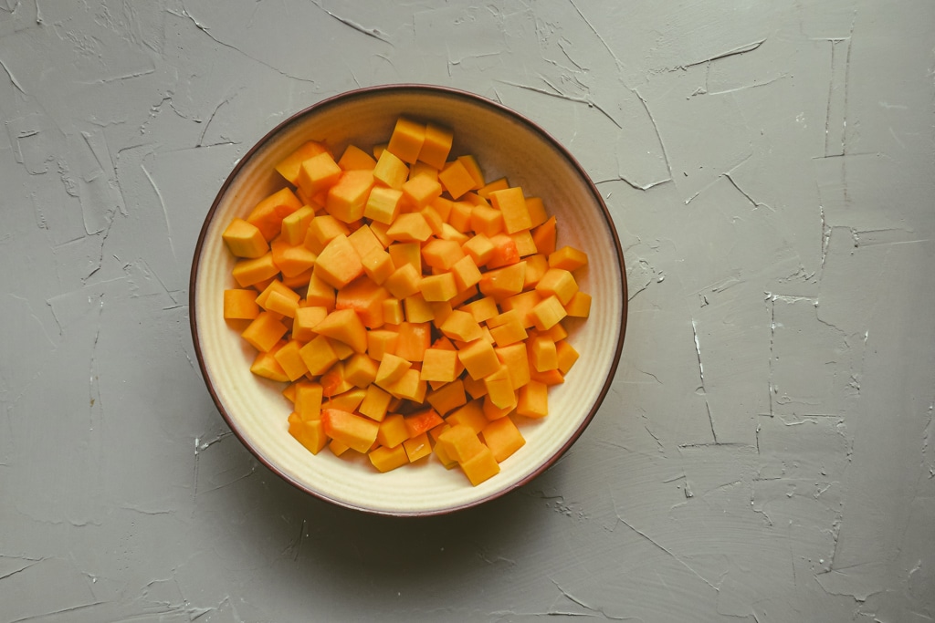 bowl of cubed butternut squash against a gray background.