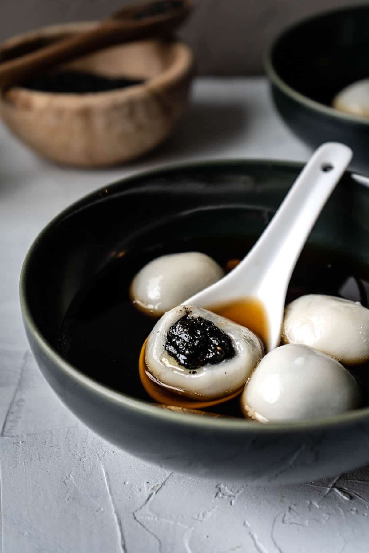 black sesame tang yuan in a dark blue bowl.