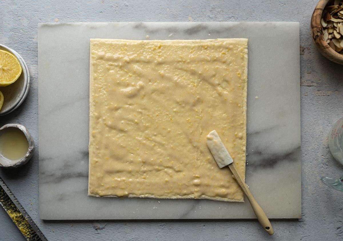 Spraying egg white/sugar mix on the puff pastry sheet with a small spatula. 