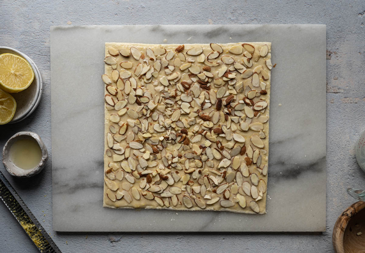 Top the puff pastry sheet with almond slices. 