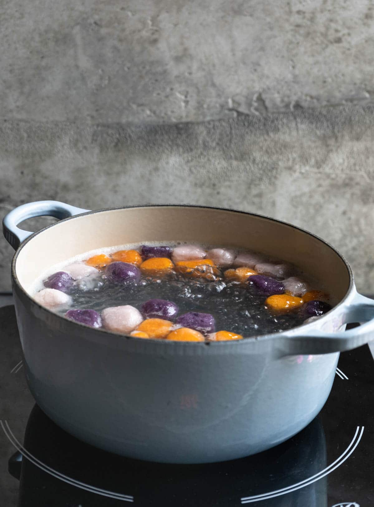 Cooking taro and sweet potato balls in a blue Dutch oven. 