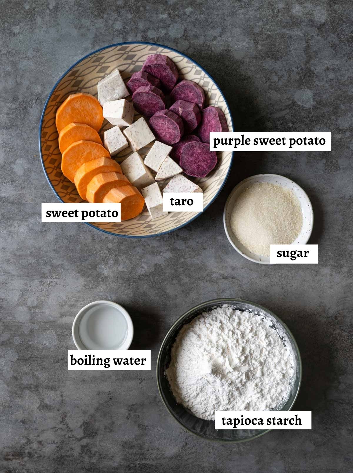 A plate of taro, sweet potato, a plate of sugar, a bowl of tapioca starch and a small bowl of water. 