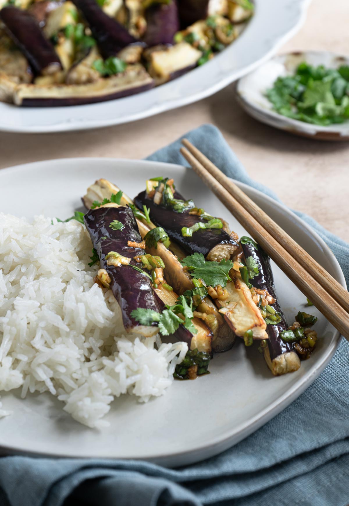 Eggplant side dish with white rice and a pair of chopsticks. 