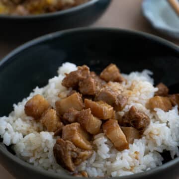 A bowl of white rice top with braised pork belly.