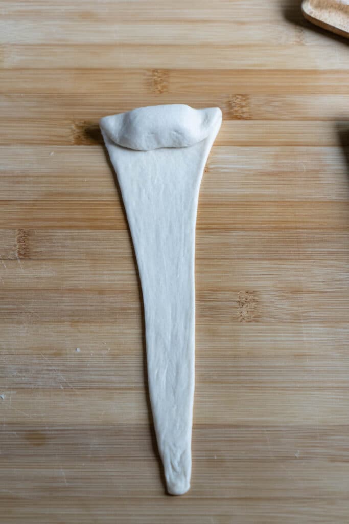 A piece of long flat triangle dough with a piece of butter folded on top.