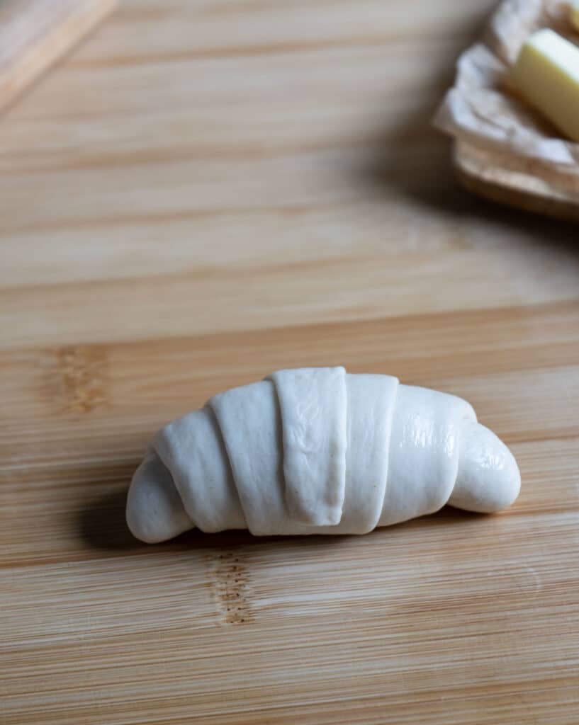 A croissant shape dough on the chopping board.
