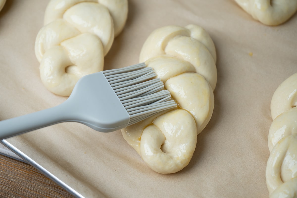 Brushing unbaked braided bread with egg wash using a gray silicon brush. 