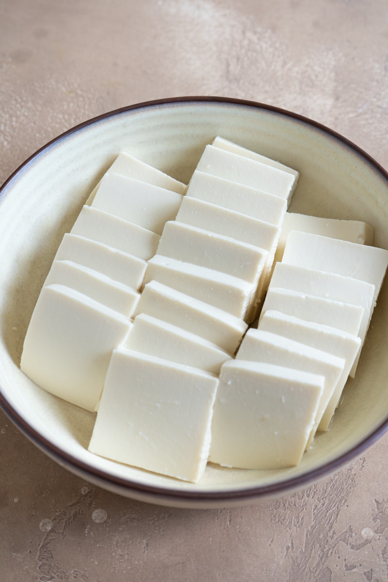 Sliced tofu neatly arranged in a bowl.