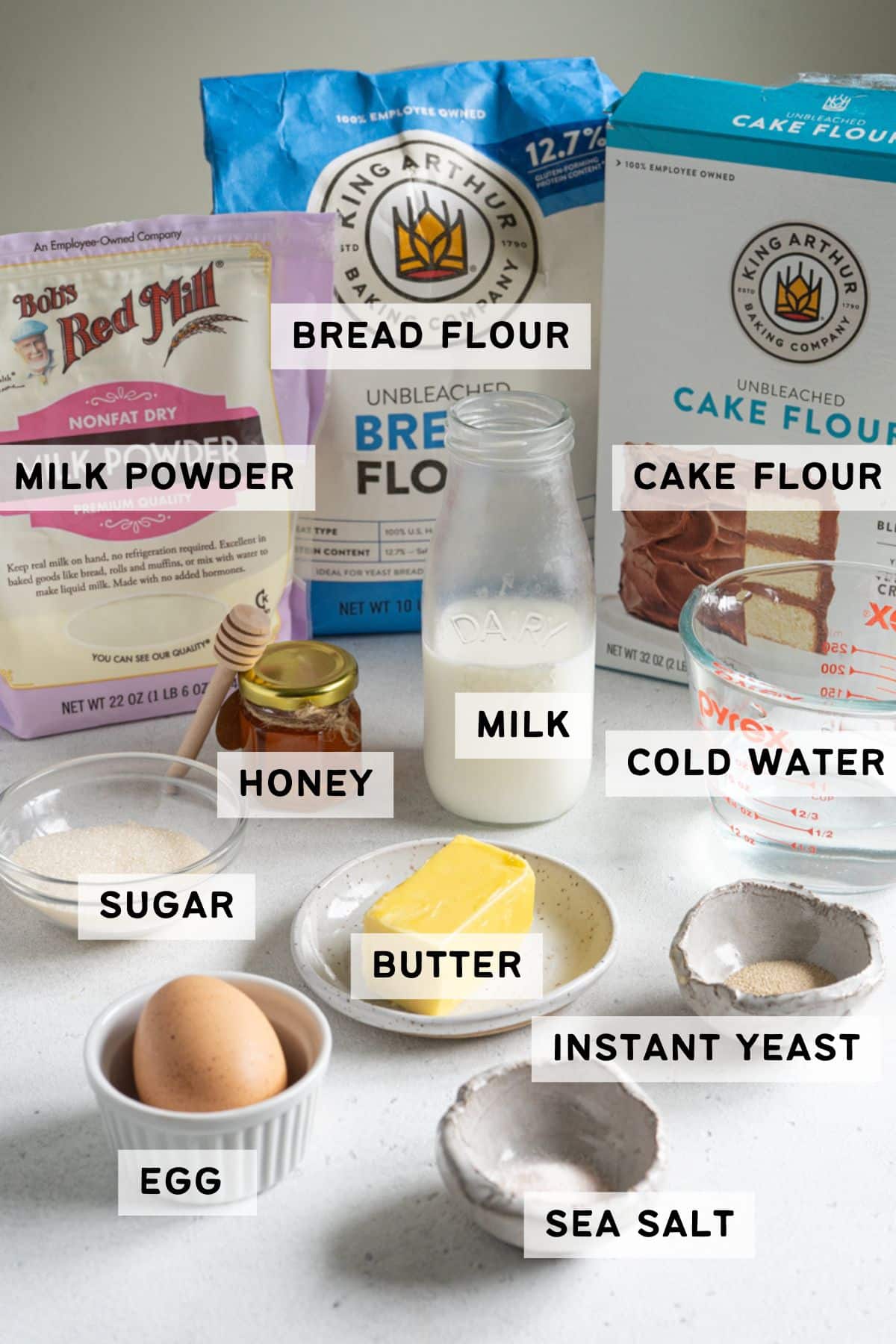 Ingredients for baking bread rolls including flour, milk, butter, egg, yeast, sugar, and salt.